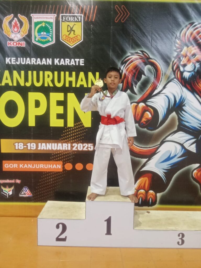 a boy in a white uniform standing on a podium with a gold medal
